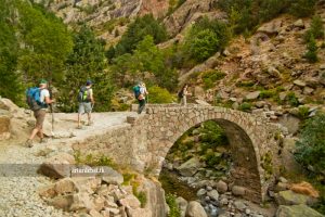 persone attraversano ponte di pietra