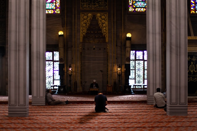 uomini seduti su tappeto rosso in moschea