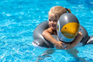 bambina bionda con ciambella in piscina