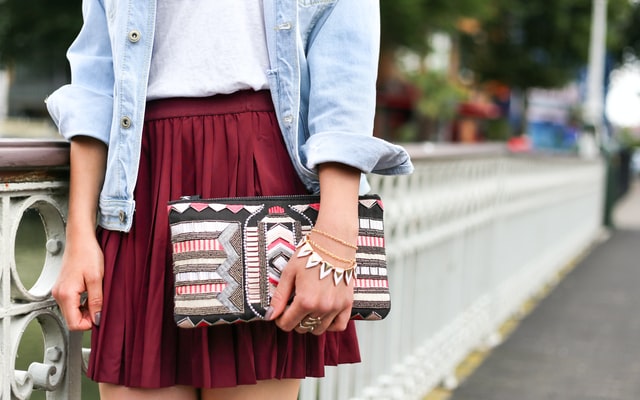 primo piano di mano di ragazza che tiene una borsa bianca nera e rosa