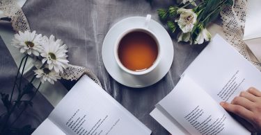 tazza di tè vicino a fiori e libri