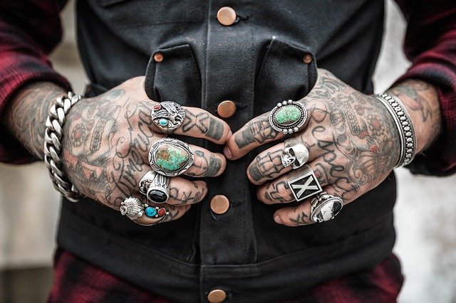 mani di uomo tatuate con anelli