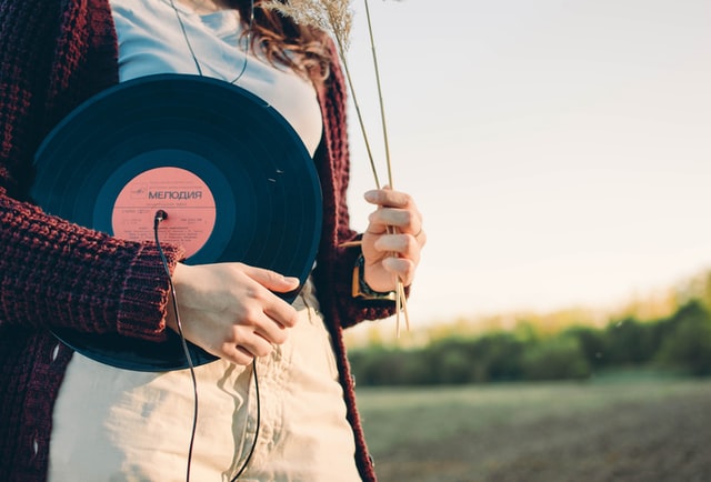 donna tiene in mano vinile all'aria aperta