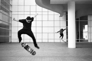 skater vestito di nero fa un trick con lo skateboard