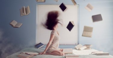 ragazza su letto e libri che volano