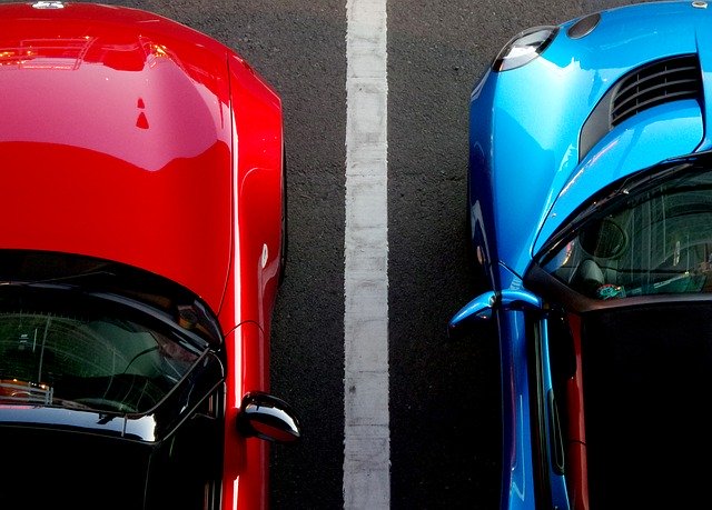 auto blu e auto rossa posteggiate a fianco