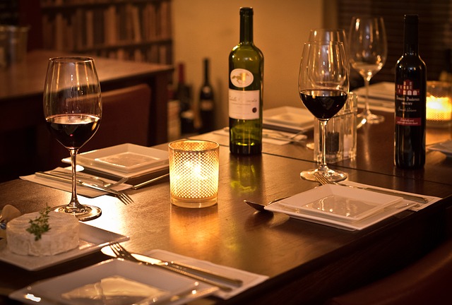 tavolo apparecchiato per due con candele e bottiglia di vino