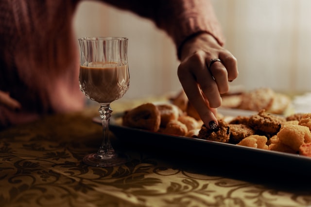 liquore dentro bicchiere di cristallo con biscotti sul tavolo