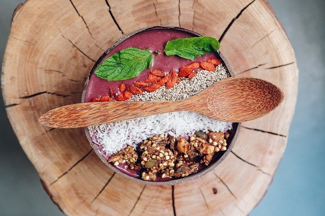 açai bowl in ciotola di legno poggiata sopra un tronco