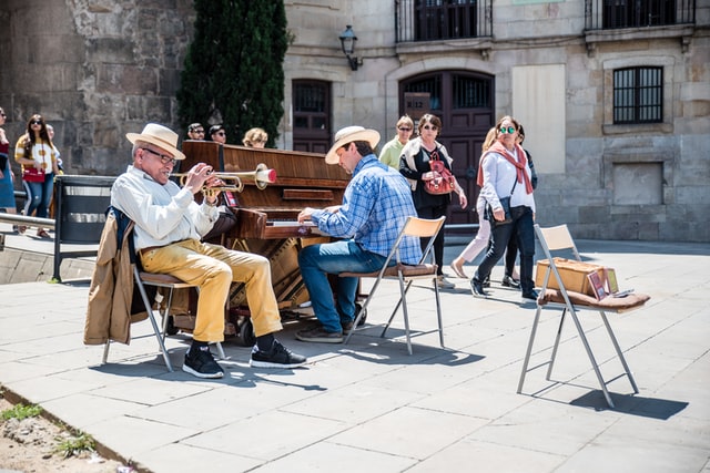 uomo che suona la tromba e uomo che suona il pianoforte in una piazza
