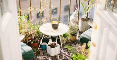 piccolo balcone con piante due sedie e un piccolo tavolino bianco con candela