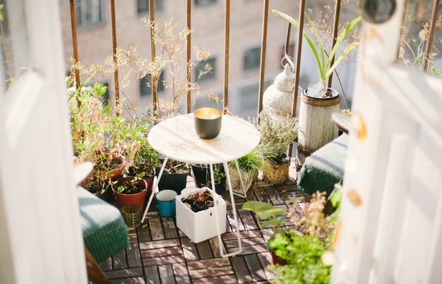 piccolo balcone con piante due sedie e un piccolo tavolino bianco con candela