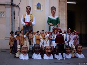 alt="persone in costume tradizionale davanti a due giganti"