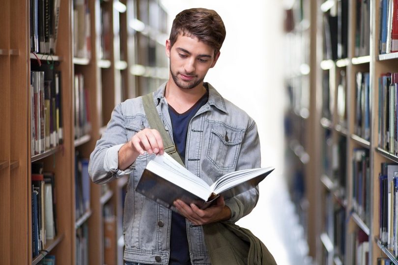 ragazzo legge libro in biblioteca