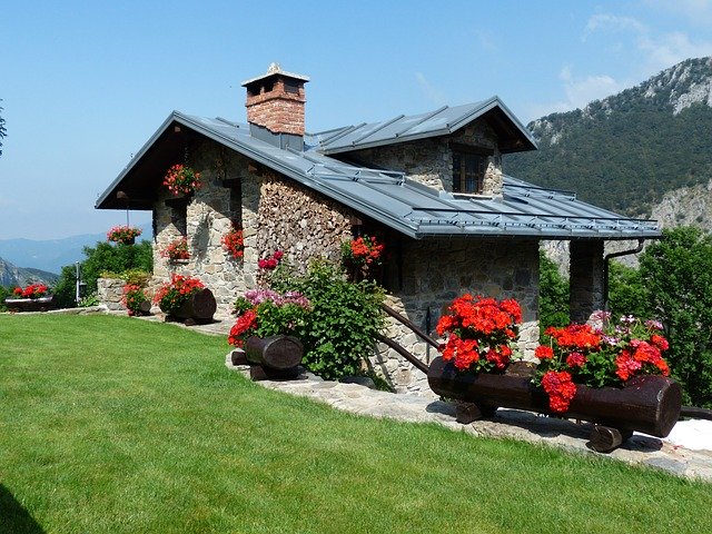 casa di mattoni con giardino con fiori rossi