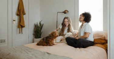 due ragazze sedute sul letto con un cane