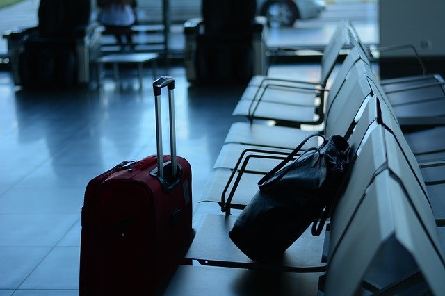 valigia rossa e zaino su sedie di aeroporto