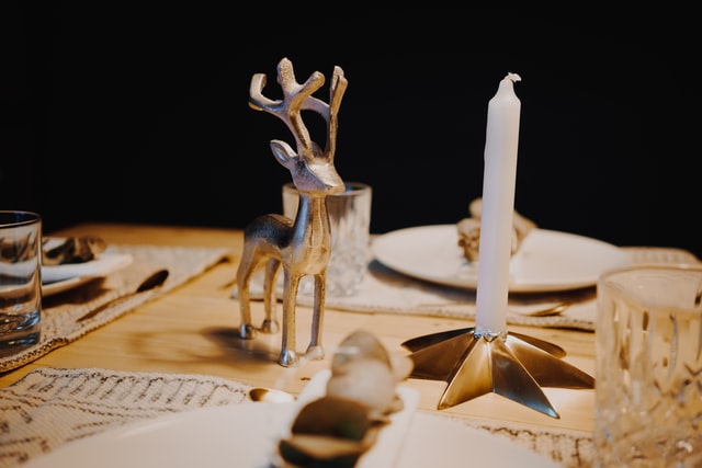 segnaposto a forma di renna su tavolo vicino a candela bianca