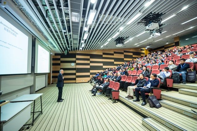 professore spiega in auditorium di università con gradoni