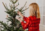ragazza bionda con camicia rossa fa l'albero di Natale