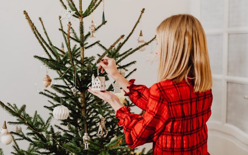 ragazza bionda con camicia rossa fa l'albero di Natale