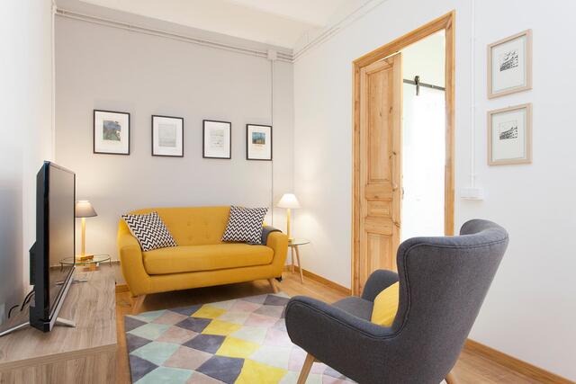 soggiorno di un appartamento con parquet tappeto divano giallo e poltrona grigia