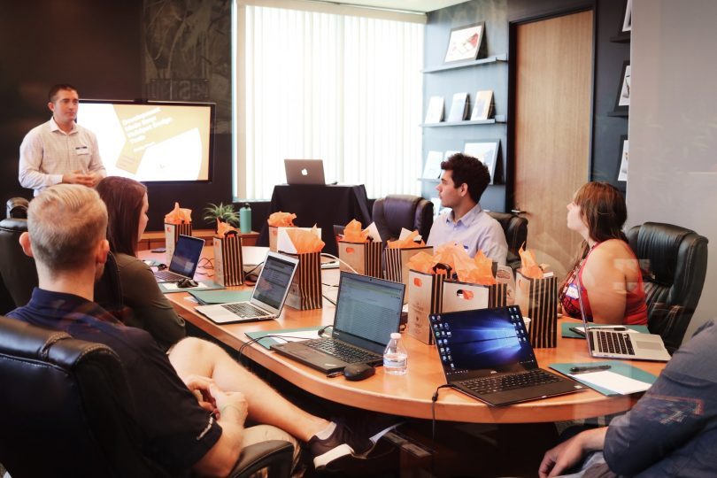 persone sedute intorno a un tavolo con computer in sala riunioni