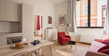 soggiorno di un appartamento con tavolo di legno divano e poltrona e mobili bianchi