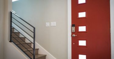 ingresso di una casa con portone rosso e scale