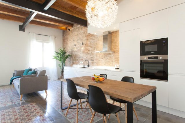 appartamento luminosi con parete in mattoni cucina bianca tavolo di legno e divano grigio