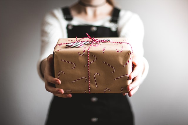 ragazza mostra regalo di natale con carta marrone