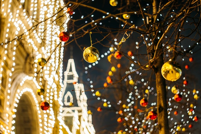albero con decorazioni di natale davanti a edificio con luci di natale di notte