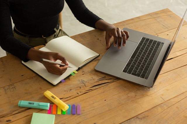 primo piano su mani di ragazza con quaderno e computer