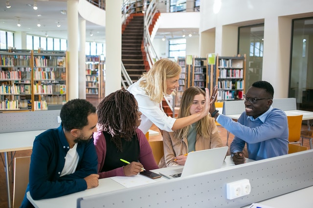 insegnante batte cinque con allievo in biblioteca