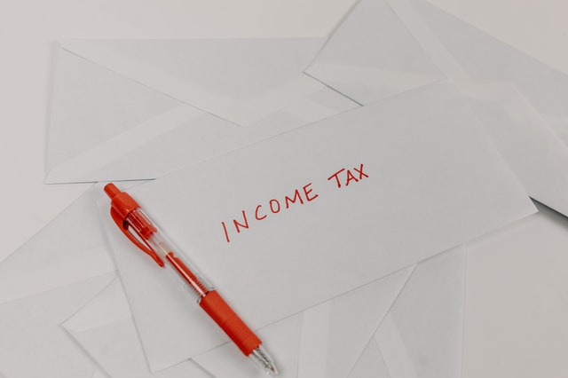 foglio con scritta rossa "income tax" e penna rossa